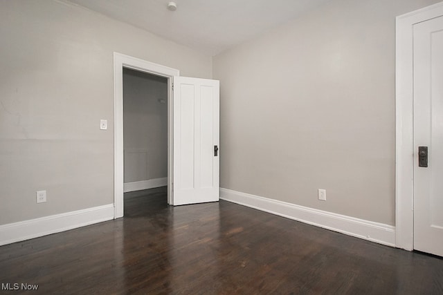 spare room featuring dark wood-style floors and baseboards