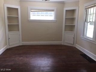 1033 Rushleigh Rd, Cleveland Heights, OH 44121 - unfurnished dining area with dark wood-style floors, built in features, and baseboards