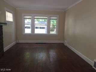 1033 Rushleigh Rd, Cleveland Heights, OH 44121 - unfurnished living room with a wealth of natural light, dark wood-style floors, baseboards, and ornamental molding