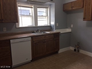 1033 Rushleigh Rd, Cleveland Heights, OH 44121 - kitchen with brown cabinetry, a sink, baseboards, and white dishwasher