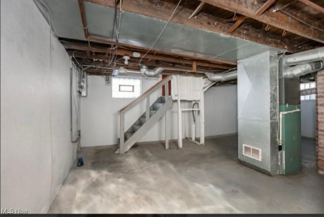 below grade area with stairs, heating unit, and visible vents