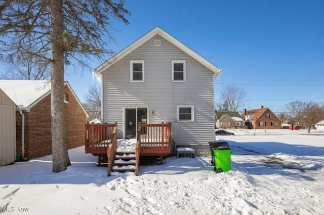 snow covered back of property featuring a wooden deck