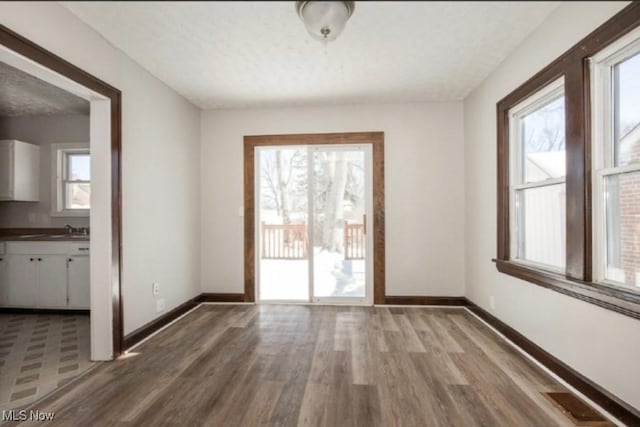unfurnished dining area featuring wood finished floors, baseboards, and a sink