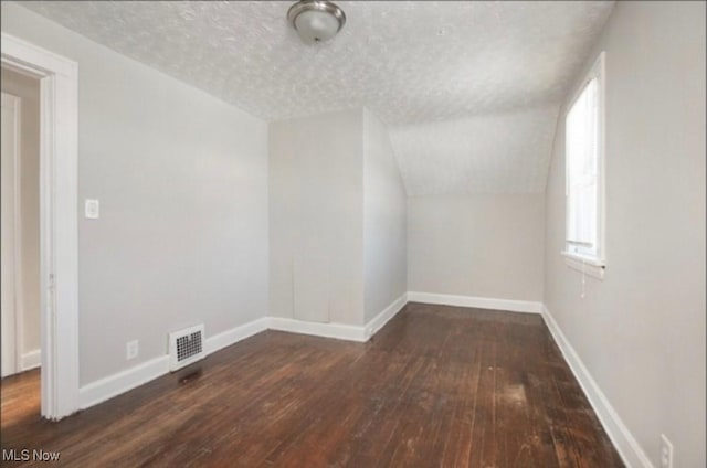 additional living space with a textured ceiling, baseboards, and wood-type flooring