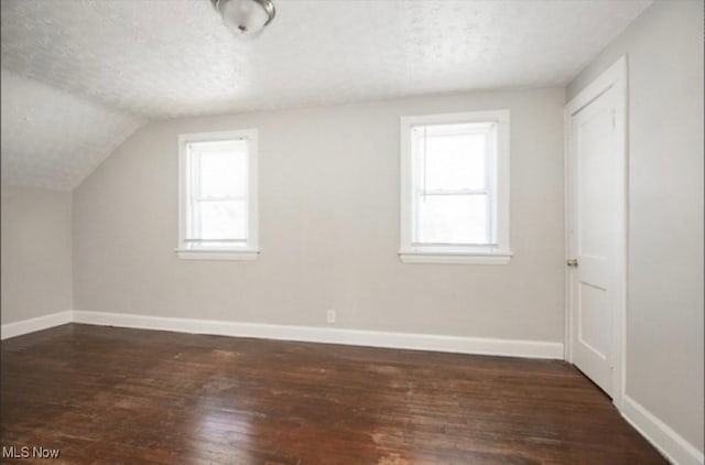 bonus room featuring lofted ceiling, wood finished floors, baseboards, and a textured ceiling