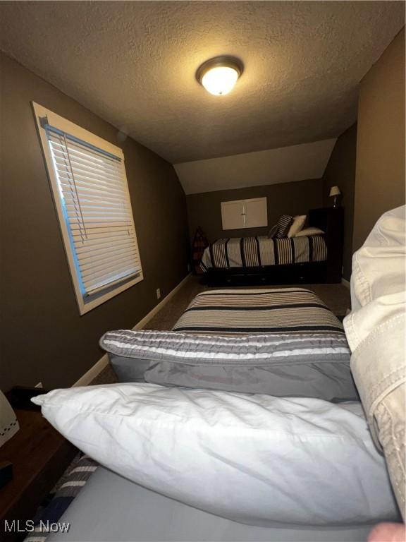 2326 Canfield Rd, Akron, OH 44312 - bedroom with baseboards, a textured ceiling, and lofted ceiling