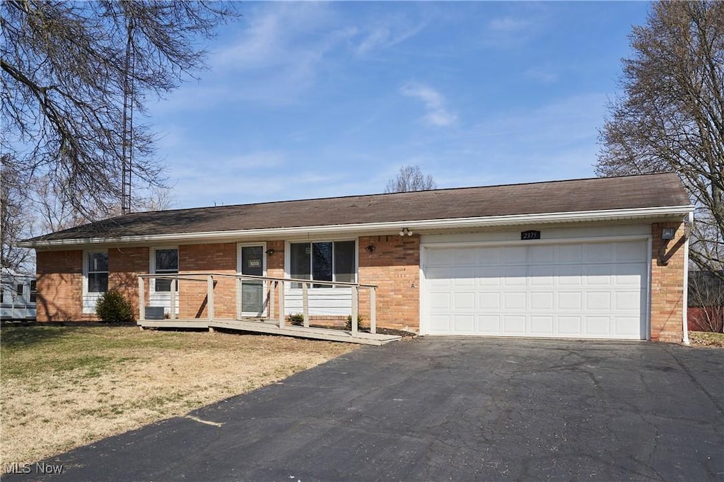view of front of house with brick siding, a front yard, an attached garage, and driveway