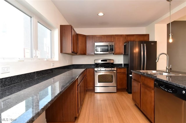 1261 W 74, Cleveland, OH 44102 - kitchen with stainless steel appliances, a sink, brown cabinets, light wood finished floors, and decorative light fixtures