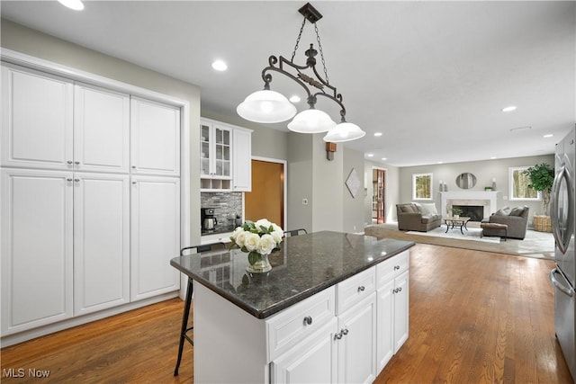 4100 Chagrin River Rd, Moreland Hills, OH 44022 - kitchen featuring a fireplace, wood finished floors, white cabinetry, a center island, and hanging light fixtures