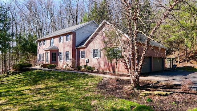 colonial house with brick siding, a front lawn, a garage, and concrete driveway