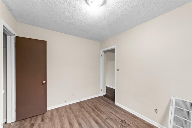 unfurnished bedroom with visible vents, baseboards, a textured ceiling, and wood finished floors
