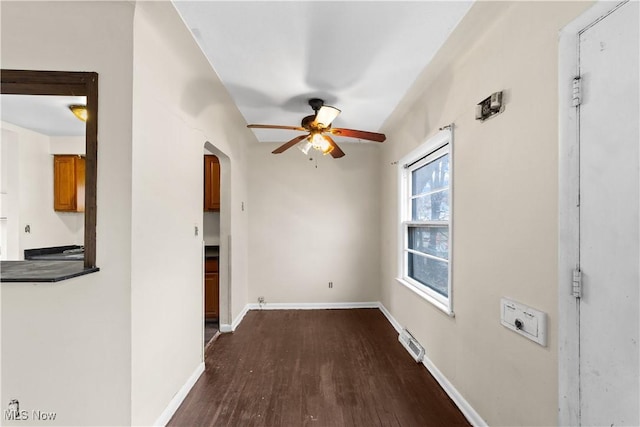 unfurnished room featuring visible vents, baseboards, ceiling fan, arched walkways, and dark wood-style floors