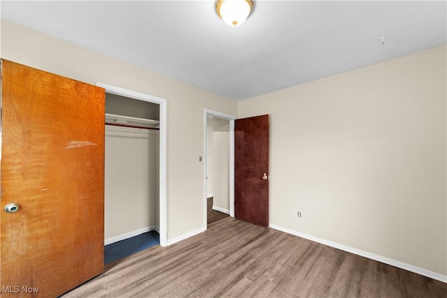 unfurnished bedroom featuring a closet, baseboards, and wood finished floors