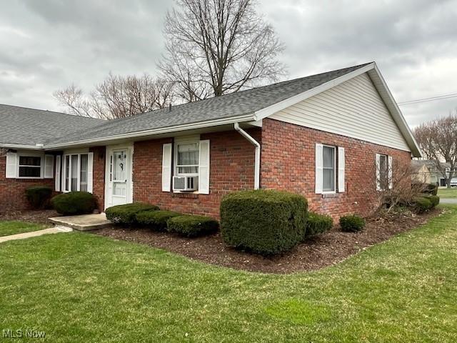 view of front of house with cooling unit, brick siding, and a front lawn