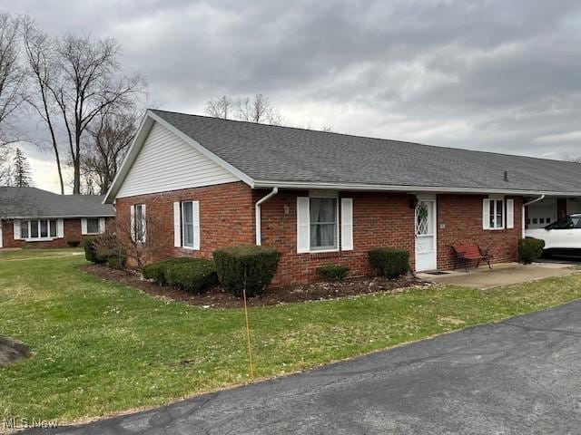 single story home with brick siding, an attached carport, and a front lawn