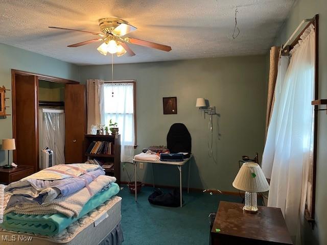 carpeted bedroom featuring ceiling fan and a textured ceiling