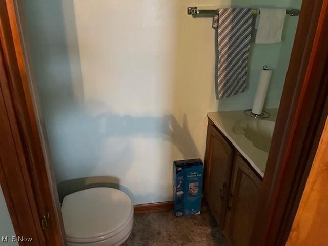 bathroom featuring baseboards, toilet, and vanity