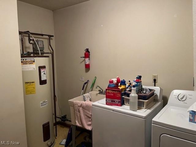 washroom featuring water heater, laundry area, and washer and clothes dryer