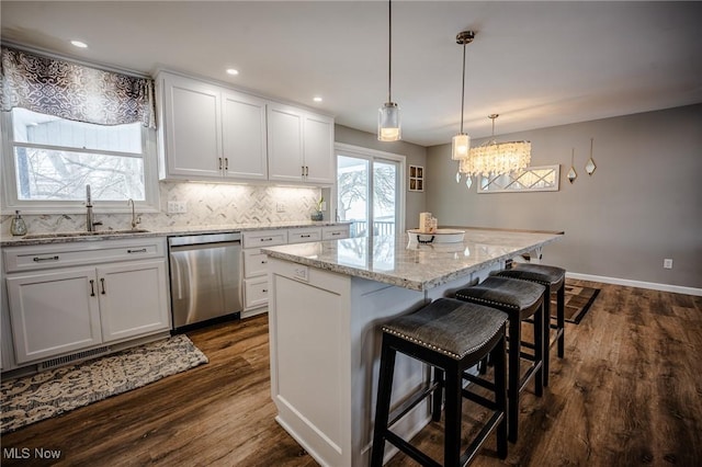 kitchen featuring dark wood-style flooring, a chandelier, a kitchen island, dishwasher, and a sink
