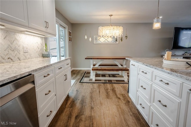 kitchen with dark wood-type flooring, backsplash, stainless steel dishwasher, and white cabinetry