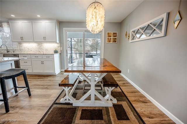 dining space with baseboards, light wood-type flooring, a notable chandelier, and recessed lighting