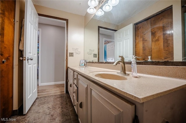 bathroom featuring double vanity, a sink, and baseboards