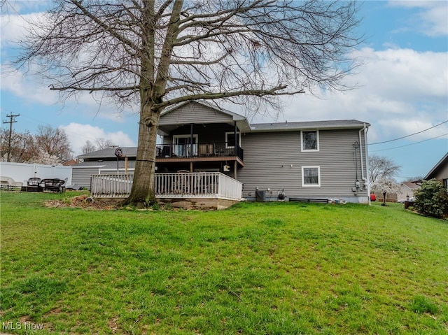 back of property with a yard, fence, and a deck