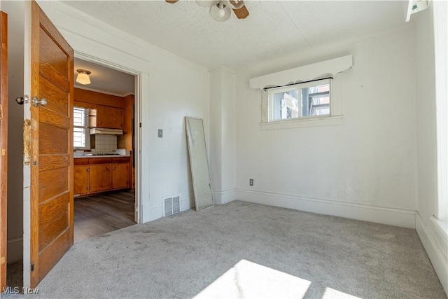 carpeted empty room featuring visible vents, baseboards, and a ceiling fan