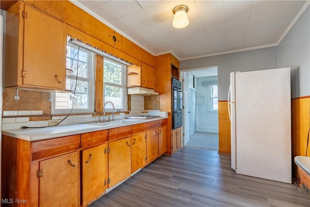 kitchen featuring crown molding, under cabinet range hood, light countertops, freestanding refrigerator, and dobule oven black