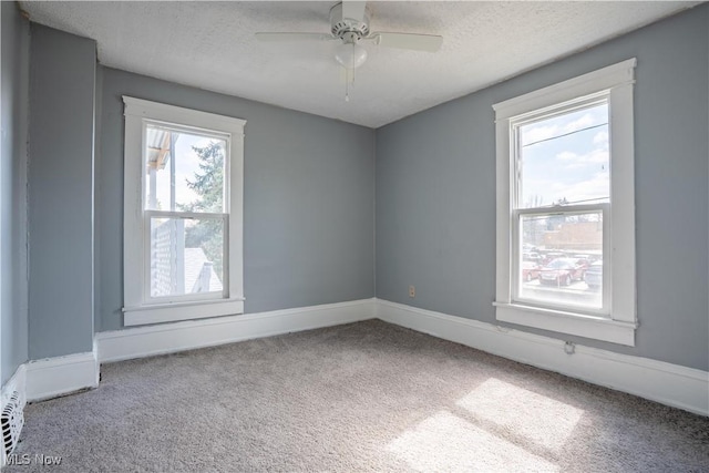 carpeted empty room with ceiling fan, baseboards, and a textured ceiling