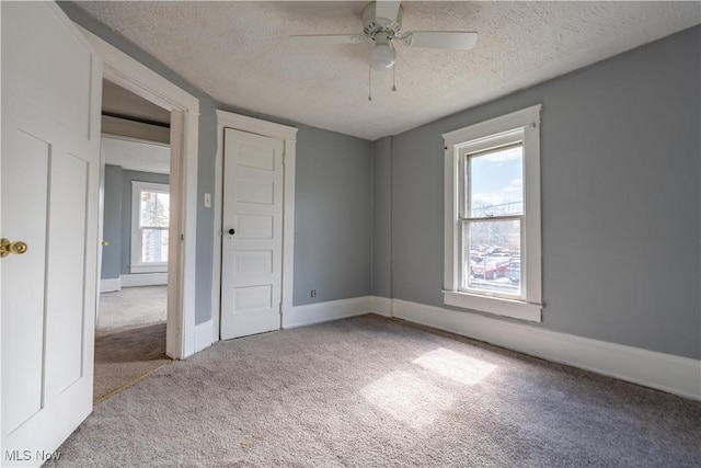 unfurnished bedroom with a ceiling fan, carpet, baseboards, and a textured ceiling