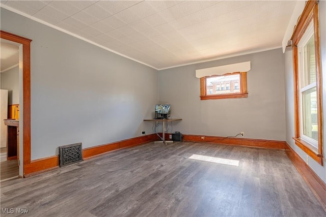 empty room with visible vents, crown molding, baseboards, and wood finished floors