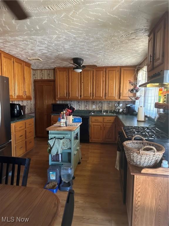 167 Andover Rd, Woodsfield, OH 43793 - kitchen with black appliances, a sink, brown cabinetry, and wood finished floors