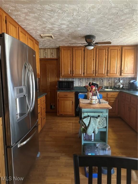 167 Andover Rd, Woodsfield, OH 43793 - kitchen featuring stainless steel refrigerator with ice dispenser, black microwave, brown cabinets, and wood finished floors