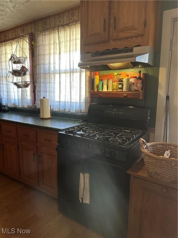 167 Andover Rd, Woodsfield, OH 43793 - kitchen featuring black range with gas cooktop, under cabinet range hood, light wood-style floors, dark countertops, and brown cabinets