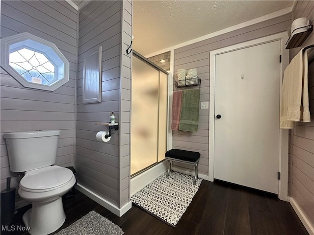 full bath featuring toilet, wood finished floors, a shower stall, and wood walls