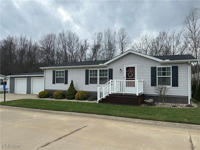 manufactured / mobile home featuring a garage, concrete driveway, and a front lawn