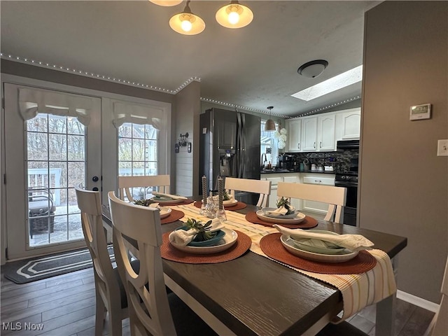 dining area with french doors, a skylight, and wood finished floors