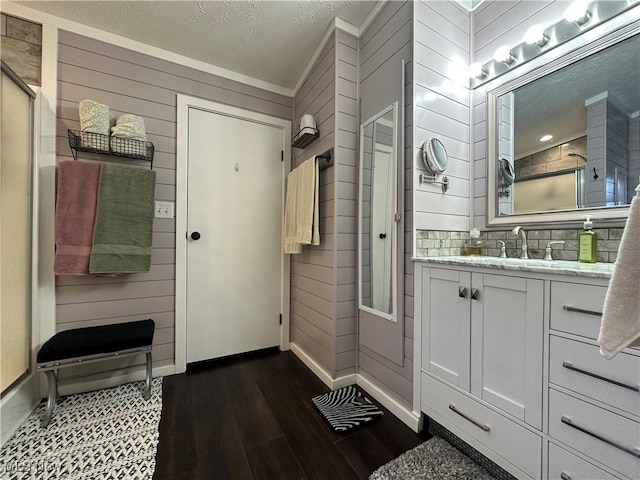 bathroom with tasteful backsplash, a shower with shower door, vanity, and wood finished floors