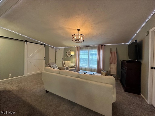living room with baseboards, a textured ceiling, a barn door, dark colored carpet, and a chandelier