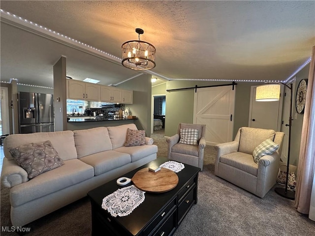 carpeted living area with a barn door, a textured ceiling, and a chandelier