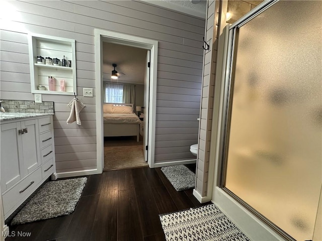 full bath featuring wooden walls, connected bathroom, a stall shower, and wood-type flooring