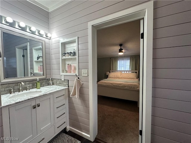 bathroom featuring vanity, wooden walls, ceiling fan, tasteful backsplash, and connected bathroom
