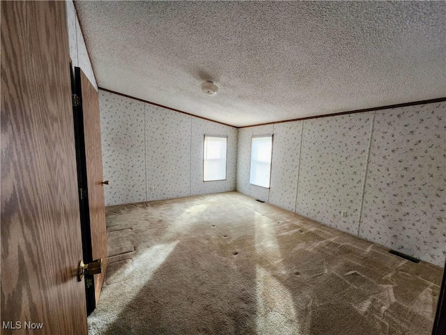 carpeted spare room with wallpapered walls, crown molding, and a textured ceiling
