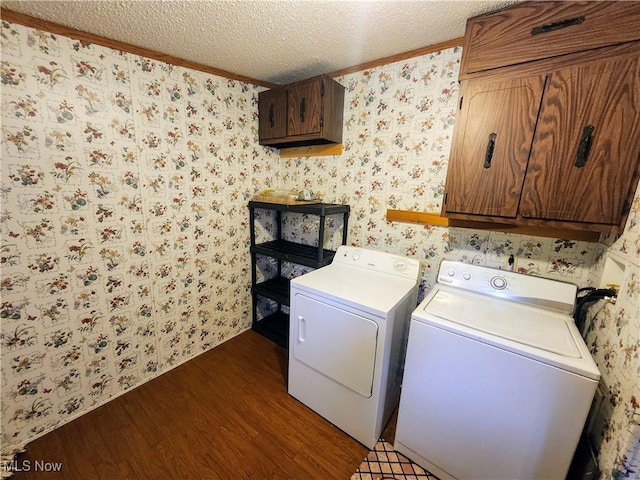 laundry room with washing machine and clothes dryer, wallpapered walls, cabinet space, dark wood-style flooring, and a textured ceiling