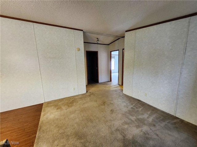 unfurnished room with a textured ceiling, carpet flooring, and crown molding