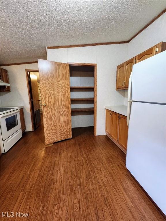 kitchen with dark wood finished floors, white appliances, light countertops, and ornamental molding