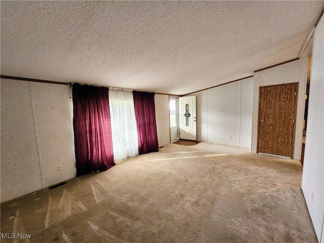 carpeted empty room featuring visible vents, a textured ceiling, and ornamental molding