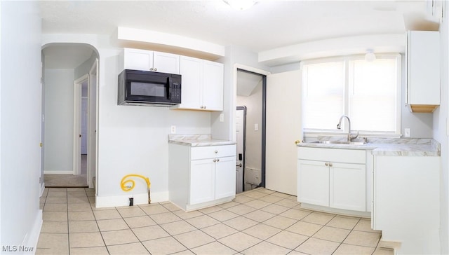 15921 Cloverside Ave, Cleveland, OH 44128 - kitchen featuring a sink, white cabinetry, light tile patterned flooring, black microwave, and light countertops
