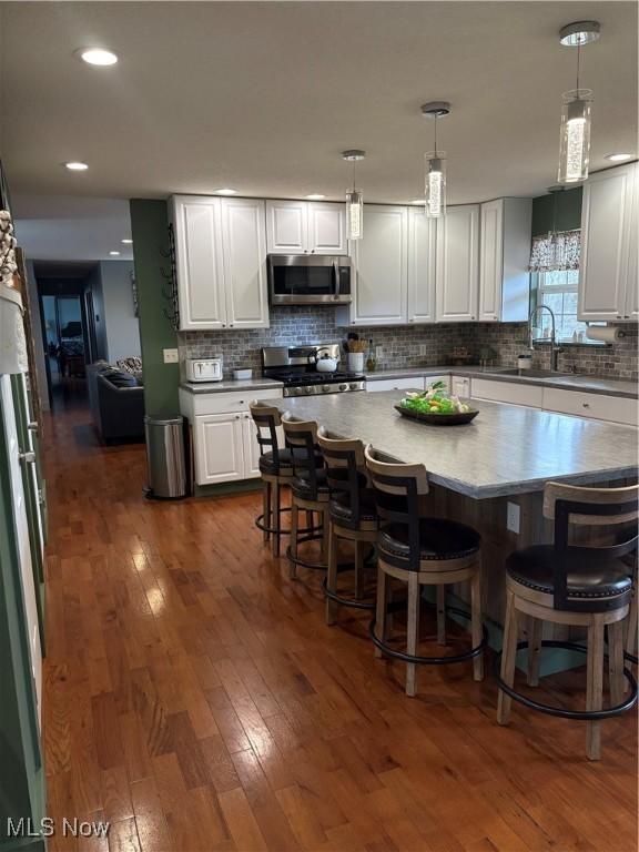 kitchen featuring stainless steel appliances, dark wood finished floors, decorative backsplash, and white cabinets